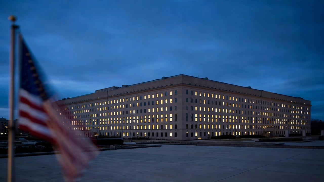 The Pentagon at dusk with an American flag in the foreground.