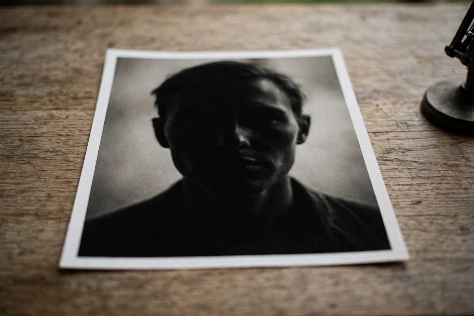 A printed photograph lying face up on a table with the face area in shadow